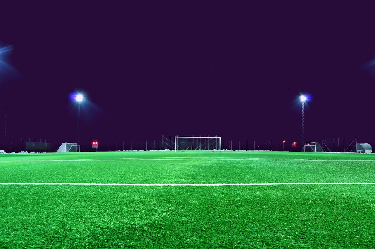 services-01 A brightly lit soccer field at night in Norrtälje, Sweden, showcasing green turf and stadium lights.